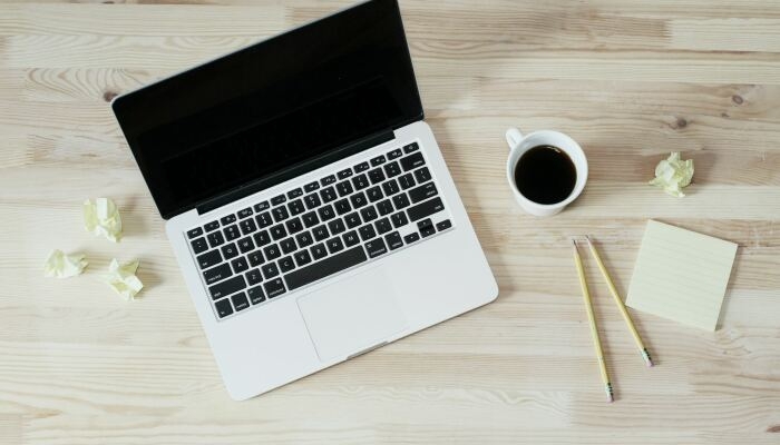 Laptop mit Kaffe, Bleistiften, Klebezettel